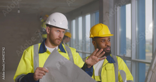 Diverse builders looking at blueprint and planning room renovation