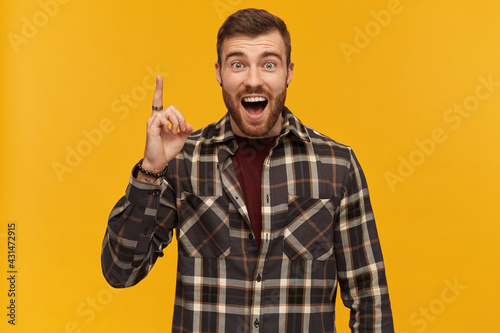 Canvas-taulu Happy exited young bearded man in plaid shirt shouting pointing up by finger and