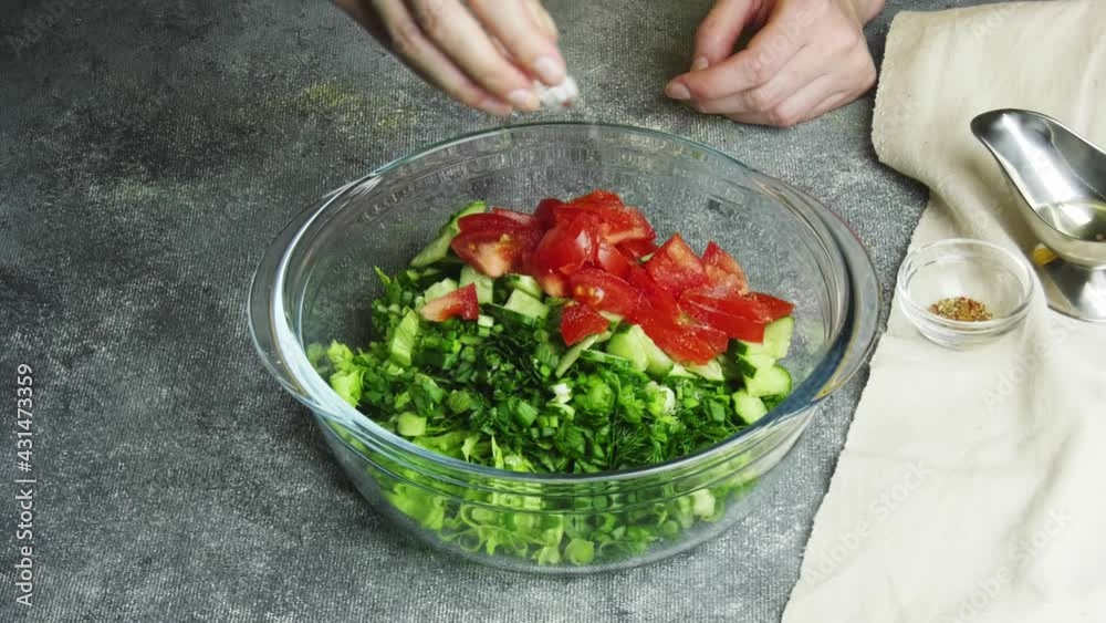 Woman adds spice to vegetable salad. Home kitchen. Woman adds spice to vegetable salad. Home kitchen.