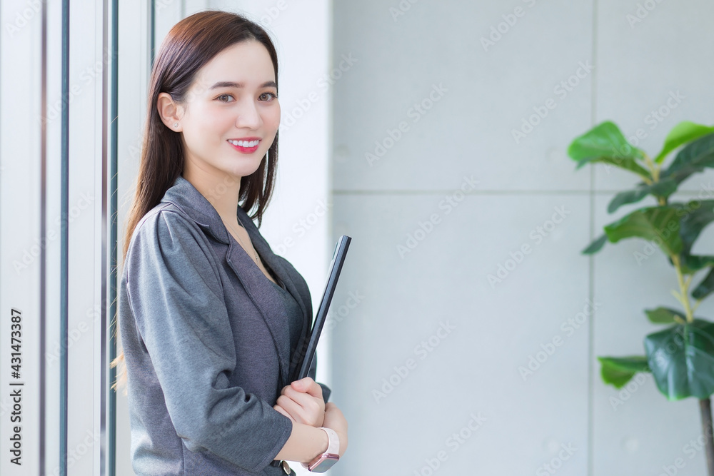 Asian business woman holds document file in her hands and smiles happily in workplace. Asian business woman holds document file in her hands and smiles happily in workplace.