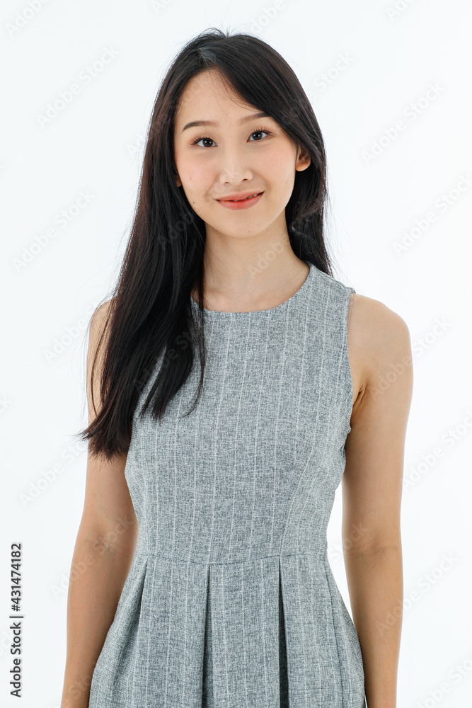 Modern young Asian business woman long black hair Chinese eyes slim looks smart in casual style by gray sleeveless dress smile standing looking at camera with white background. Modern young Asian business woman long black hair Chinese eyes slim looks smart in casual style by gray sleeveless dress smile standing looking at camera with white background.