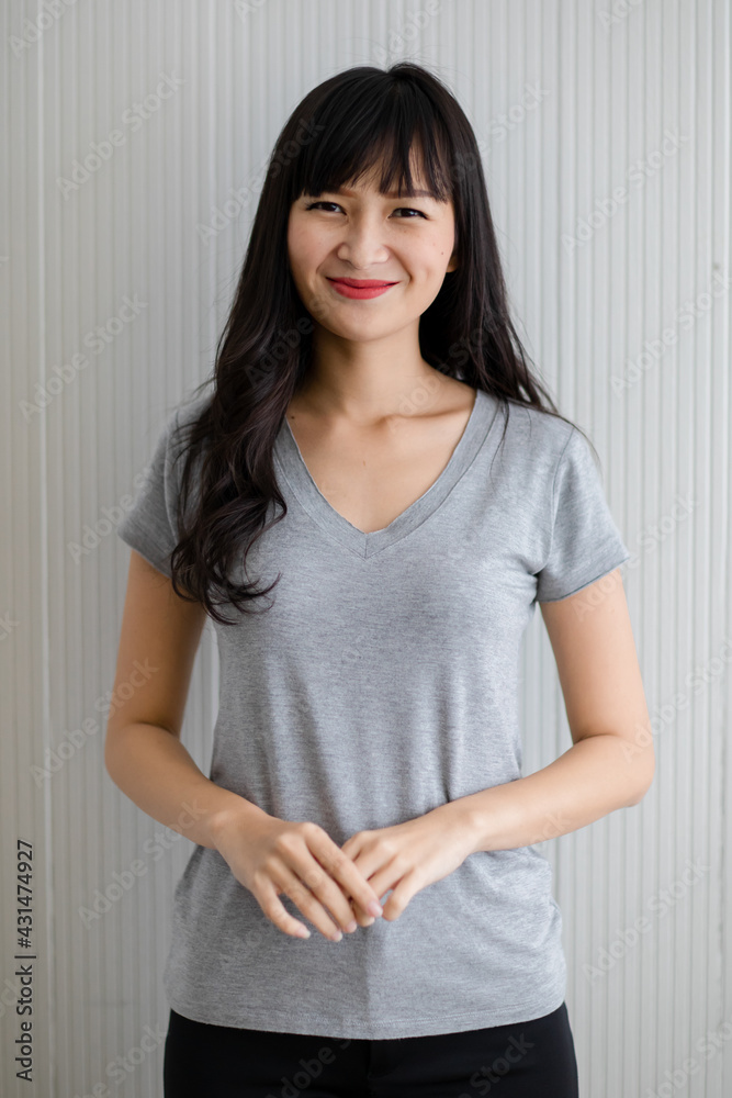 Beautiful girl with long black hair with red lips Wear a V-neck T-shirt Smiling standing looking at the camera Hands neatly clasped in front, look cute and friendly.