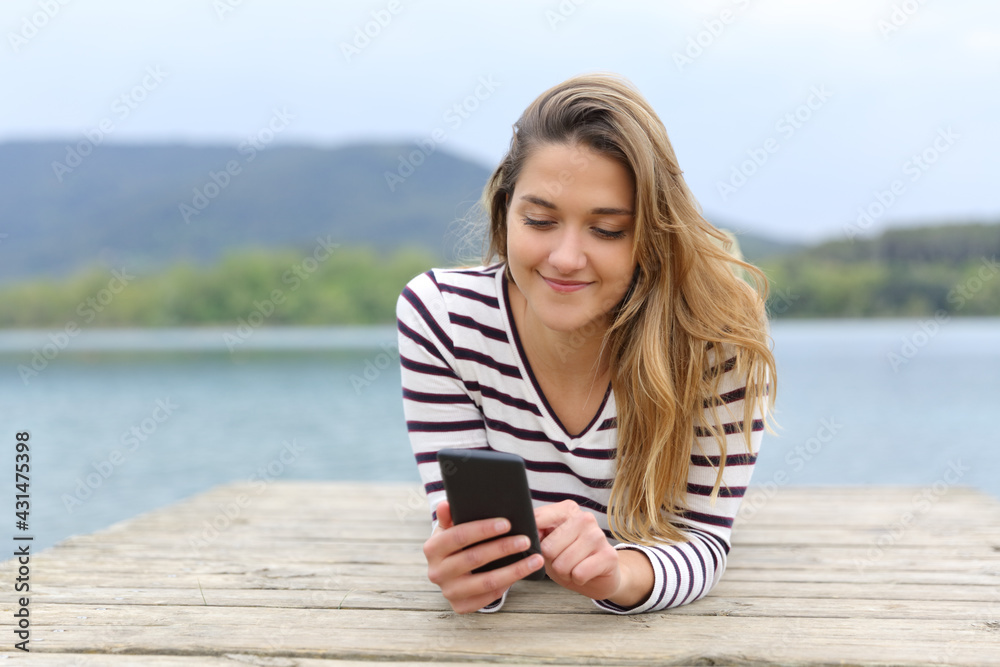 Woman using smartphone in a lake pier Woman using smartphone in a lake pier