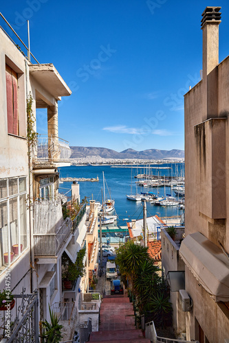 Fototapeta Naklejka Na Ścianę i Meble -  A narrow street in Athens with view to Piraeus Port and the Aegean Sea, Greece