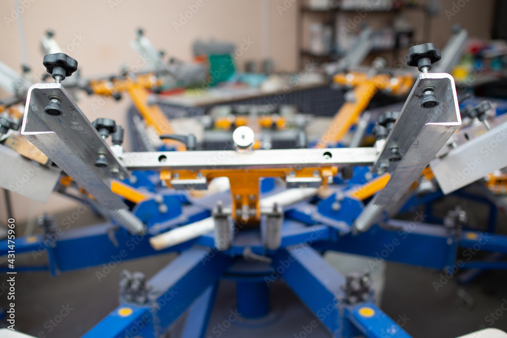 Serigraphy silk screen print process at clothes factory. Carousel Frame, squeegee and plastisol color paints. Serigraphy silk screen print process at clothes factory. Carousel Frame, squeegee and plastisol color paints.