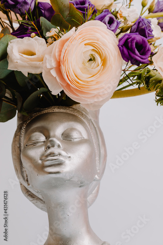 Woman face in the shape of a vase for flowers with Anemone eustoma ranunculus. photo