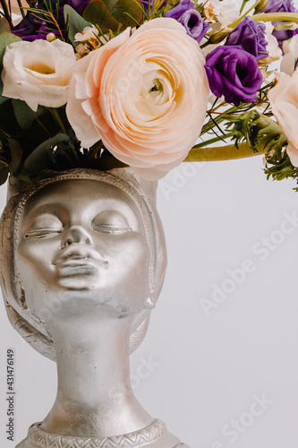Woman face in the shape of a vase for flowers with Anemone eustoma ranunculus.