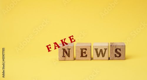 wooden cubes with the inscription false news on a yellow background. The concept of information hygiene, propaganda, debunking of myths and false information photo