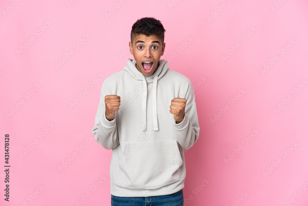 Young Brazilian man isolated on pink background celebrating a victory in winner position Young Brazilian man isolated on pink background celebrating a victory in winner position