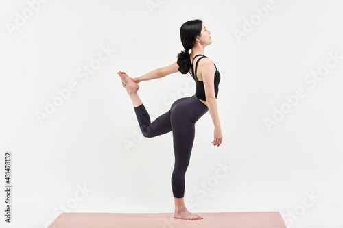 Asia korean girl long haired beautiful pilates or yoga athlete does a graceful pose while wearing a tight sports outfit against a white background in a studio