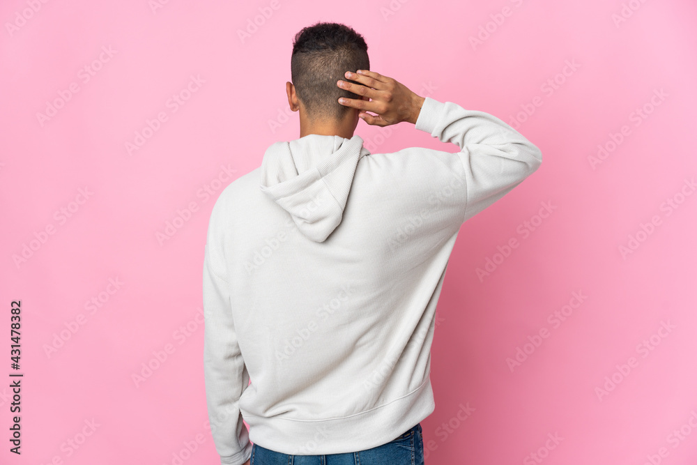 Young Brazilian man isolated on pink background in back position and thinking Young Brazilian man isolated on pink background in back position and thinking