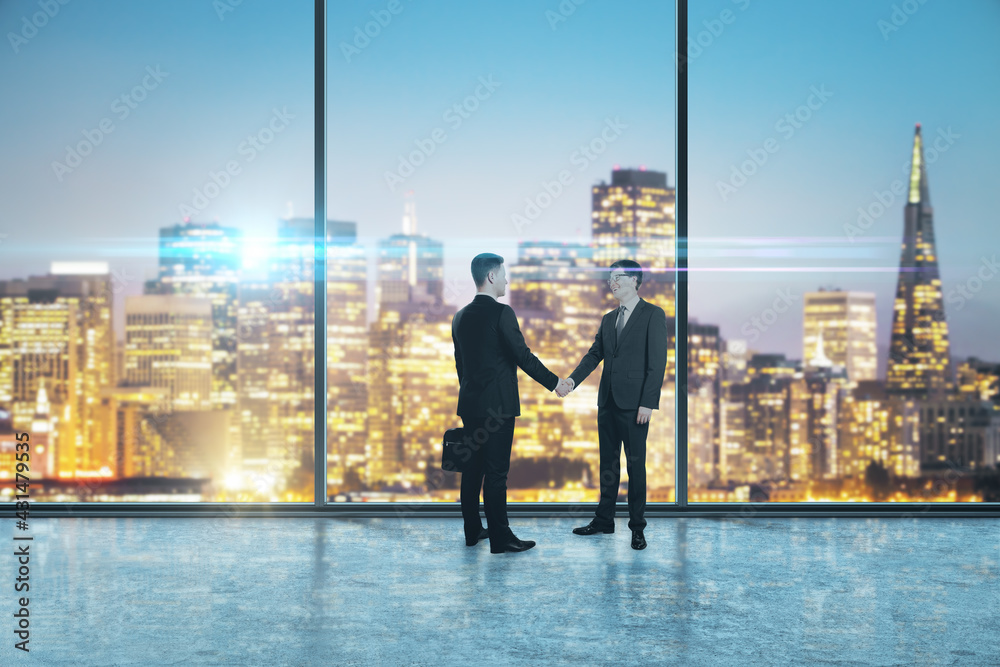 Two businessmen shaking hands in an empty big office room with big windows and night city view, reaching an agreement. Communication and cooperation concept