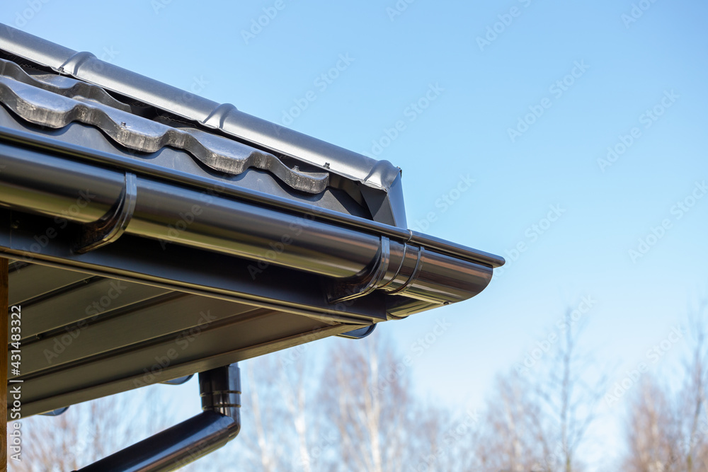 Corner of the new modern house with roof, gutter and wooden shutter under blue sky Corner of the new modern house with roof, gutter and wooden shutter under blue sky
