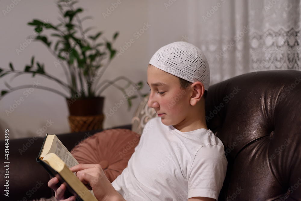 Muslim boy in dress traditional Muslim. reading an al-Quran holy book in Ramadan month.