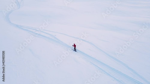 Cross country skier traveling across a snowy arctic tundra in the high mountains on a cold winters day.
