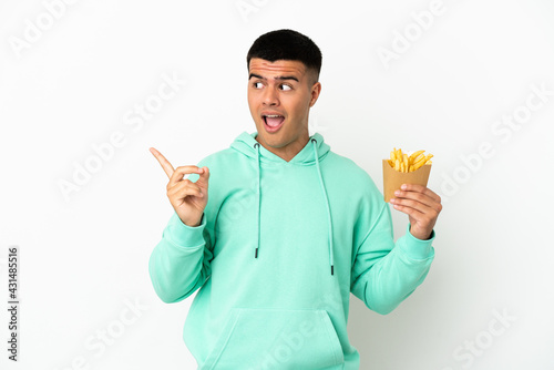 Young handsome man holding fried chips over isolated white background intending to realizes the solution while lifting a finger up