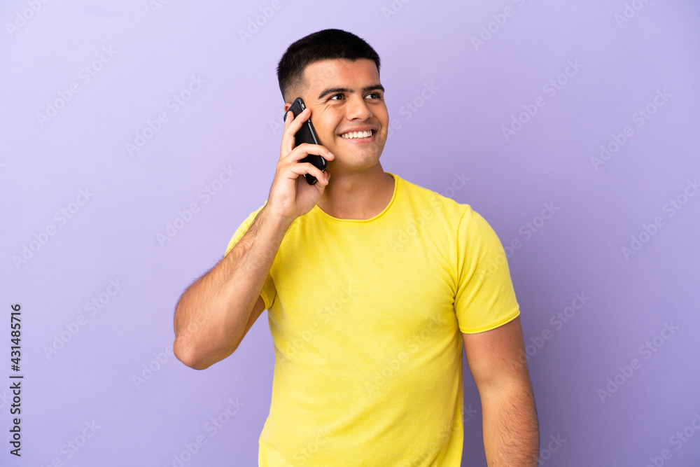 Young handsome man using mobile phone over isolated purple background thinking an idea while looking up Young handsome man using mobile phone over isolated purple background thinking an idea while looking up