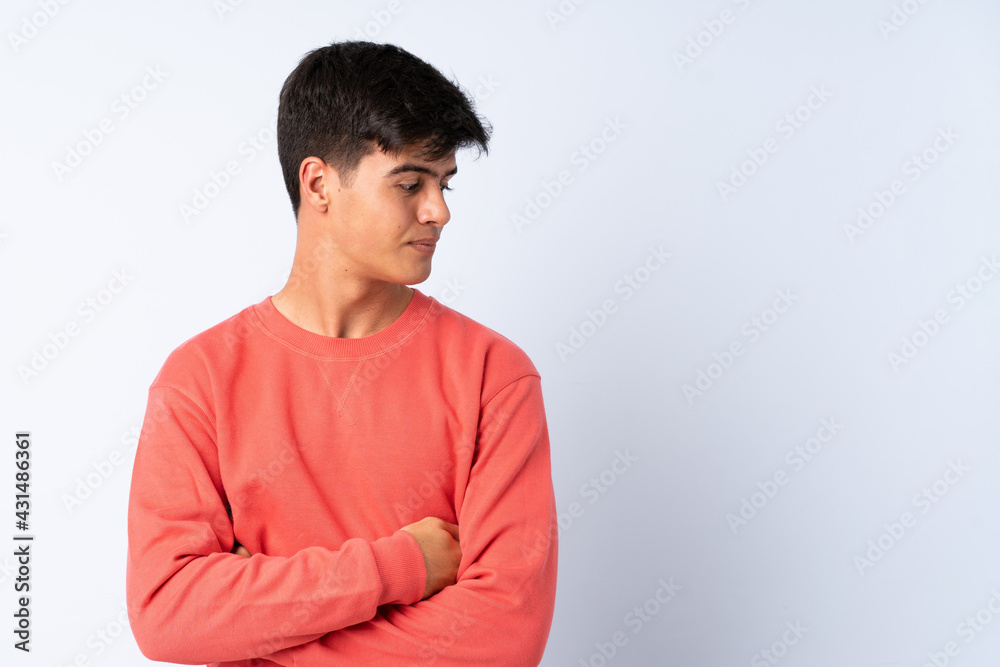 Handsome man over isolated blue background having doubts while looking side Handsome man over isolated blue background having doubts while looking side