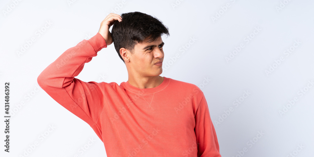 Handsome man over isolated blue background having doubts while scratching head Handsome man over isolated blue background having doubts while scratching head