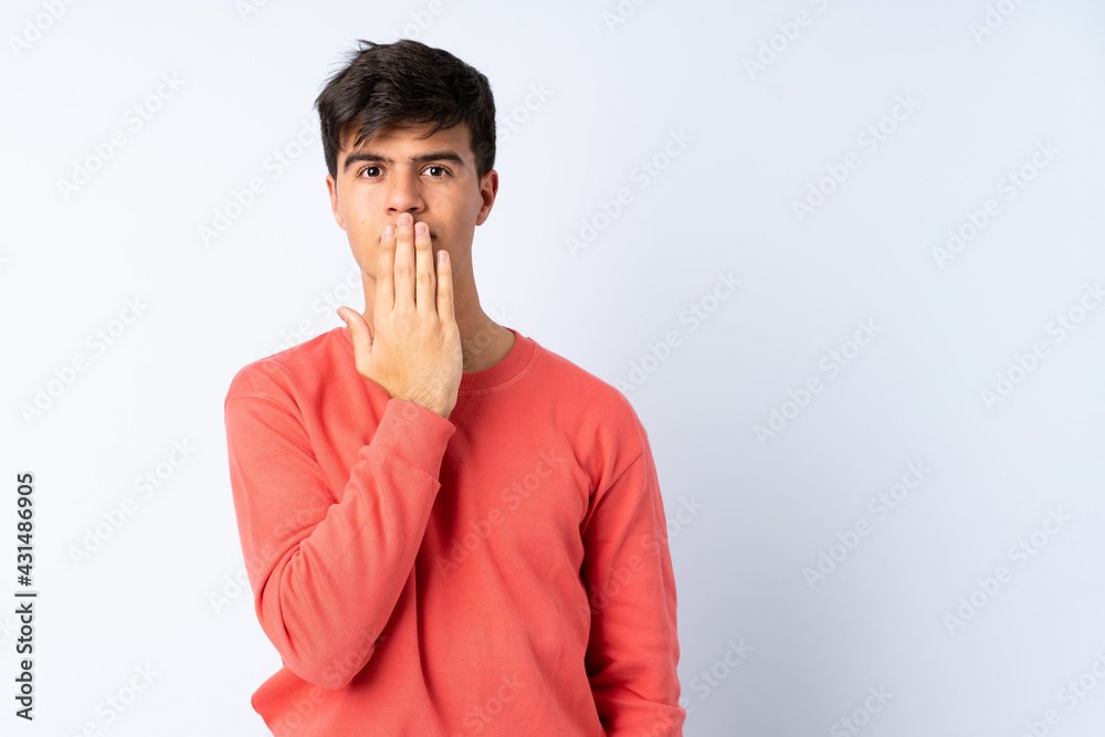 Handsome man over isolated blue background covering mouth with hand Handsome man over isolated blue background covering mouth with hand