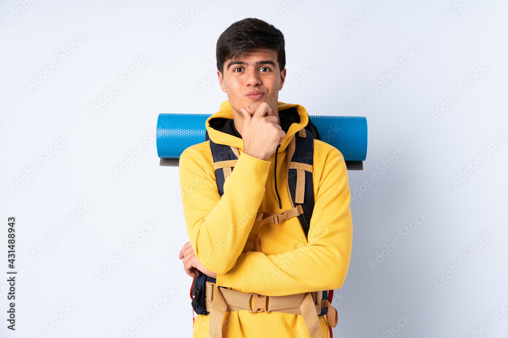 Young mountaineer man with a big backpack over isolated blue background laughing Young mountaineer man with a big backpack over isolated blue background laughing