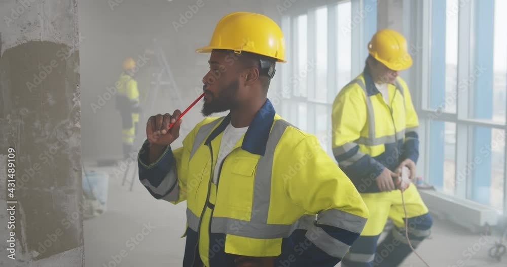 Afro-american builder drawing measurement on wall with pen Afro-american builder drawing measurement on wall with pen