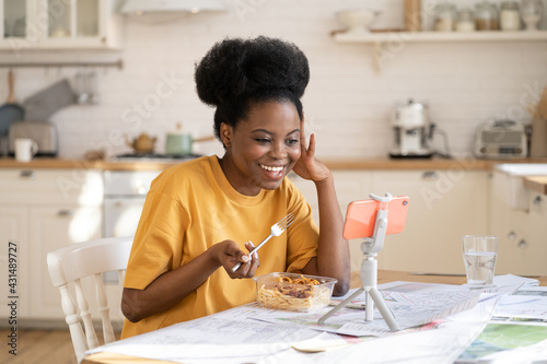 Smiling african woman happy to talk with friend via video call at dinner or break from work at home. Social distancing under covid-19 epidemic concept. Black female communicate with video conference