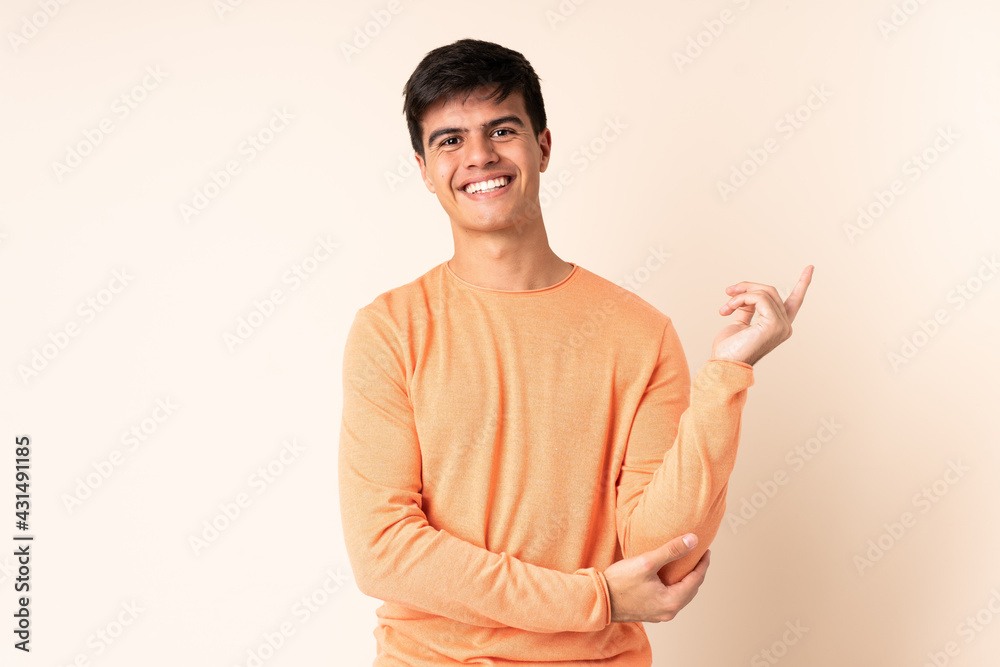 Handsome man over isolated beige background happy and pointing up Handsome man over isolated beige background happy and pointing up