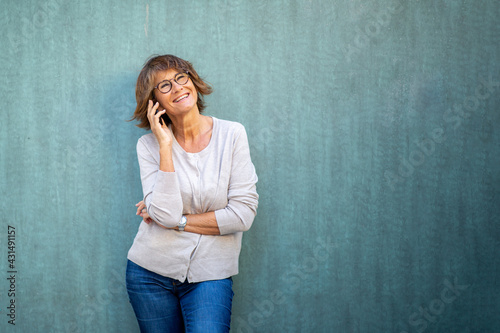 older woman talking with mobile phone by green background