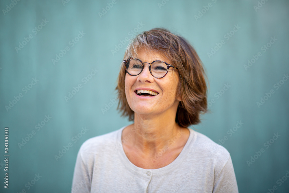 Close up happy woman with glasses laughing by green wall