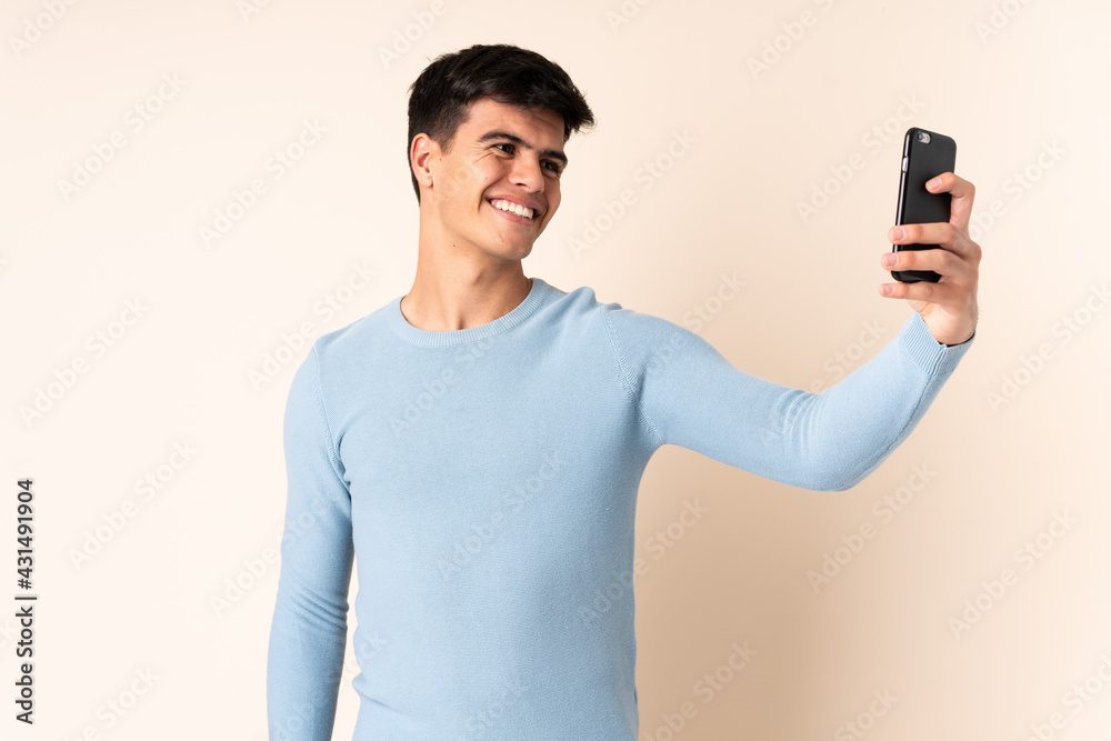 Handsome man over isolated beige background making a selfie Handsome man over isolated beige background making a selfie