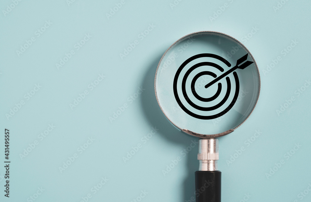 Target board inside of magnifier glass for focus business objective on blue background and copy space. - obrazy, fototapety, plakaty 