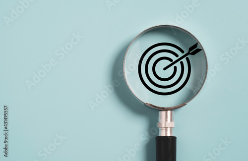 Target board inside of magnifier glass for focus business objective on blue background and copy space. photo
