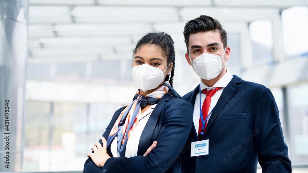Young flight attendants looking at camera in airport lounge, coronavirus, travel and new normal. Young flight attendants looking at camera in airport lounge, coronavirus, travel and new normal.