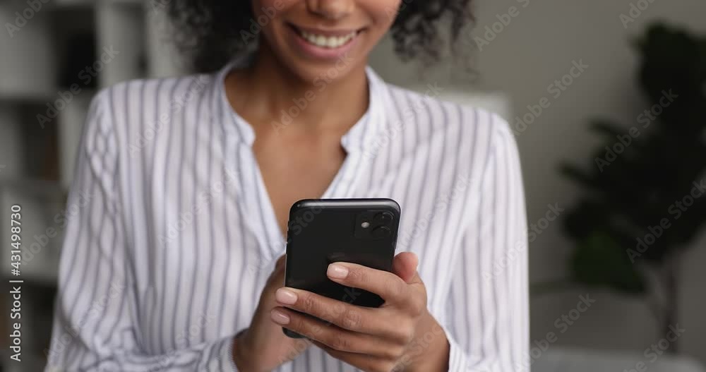 Cheerful African female standing indoor holding in hands cell use smartphone close up cropped view. Social media network new cool mobile application, retail web sites, e-dating services usage concept Cheerful African female standing indoor holding in hands cell use smartphone close up cropped view. Social media network new cool mobile application, retail web sites, e-dating services usage concept