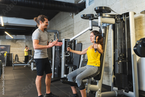 Personal trainer helping young female athlete in the gym.
