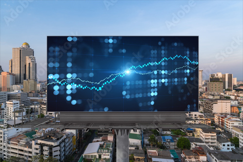 Glowing FOREX graph hologram on billboard, aerial panoramic cityscape of Bangkok at sunset. Stock and bond trading in Southeast Asia. The concept of fund management.