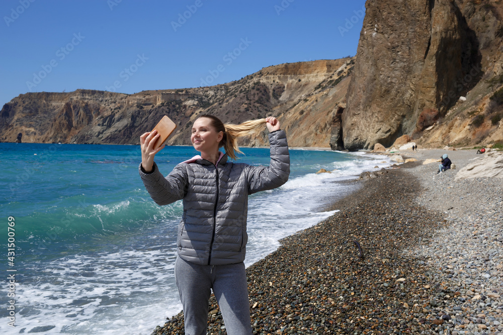 a young woman takes a selfie by the ocean