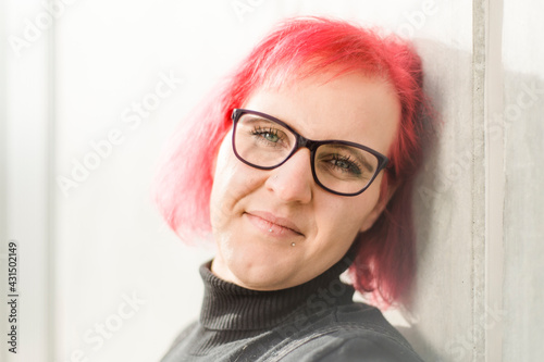 Tableau sur toile Eine schöne junge Frau mit roten Haaren, Brille und Piercing schaut traurig in d