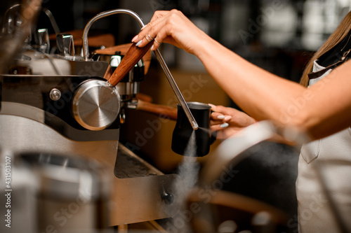 view on barista's hand that turns on coffee machine to releases steam for making drink