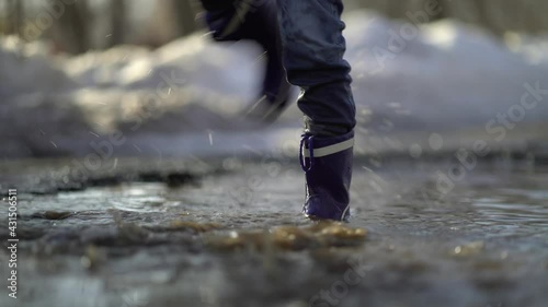 happy boy rubber boots have fun playing in a puddl photo