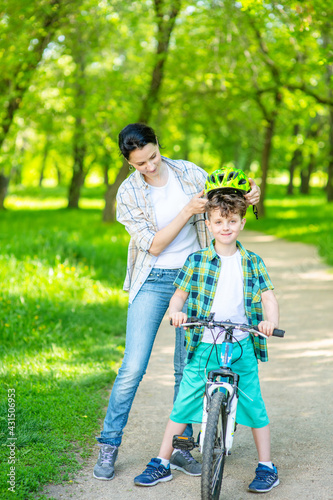 The child looks at his mother holding out his bicycle helmet. Safe Leisure Concept