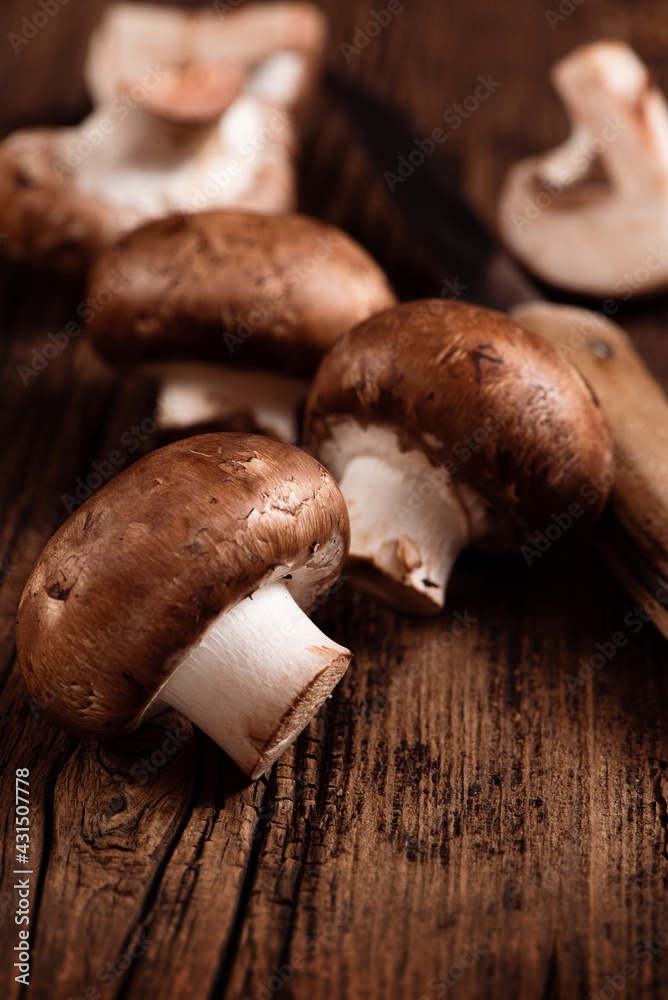 Cremini mushrooms on textured wood background. Baby portobello. Closeup. Selective focus.