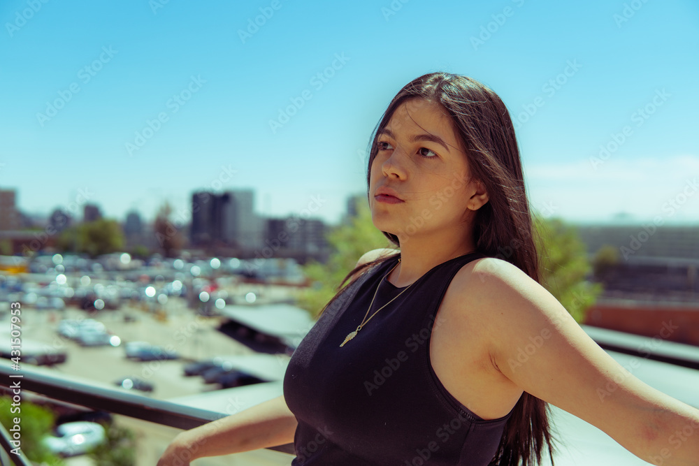 Young girl leaning on a railing with the city of madrid in the background.