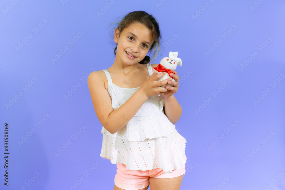 Cute little girl with rabbit plush isolated over purple background Cute little girl with rabbit plush isolated over purple background