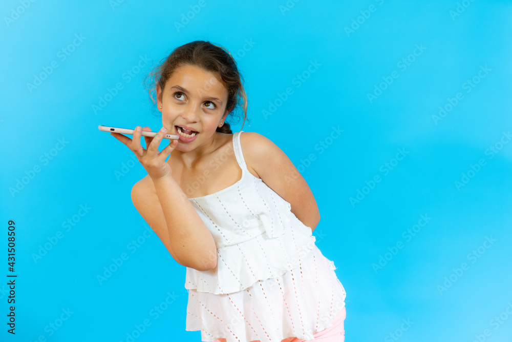 Little girl talking on mobile phone isolated over blue background. Little girl talking on mobile phone isolated over blue background.