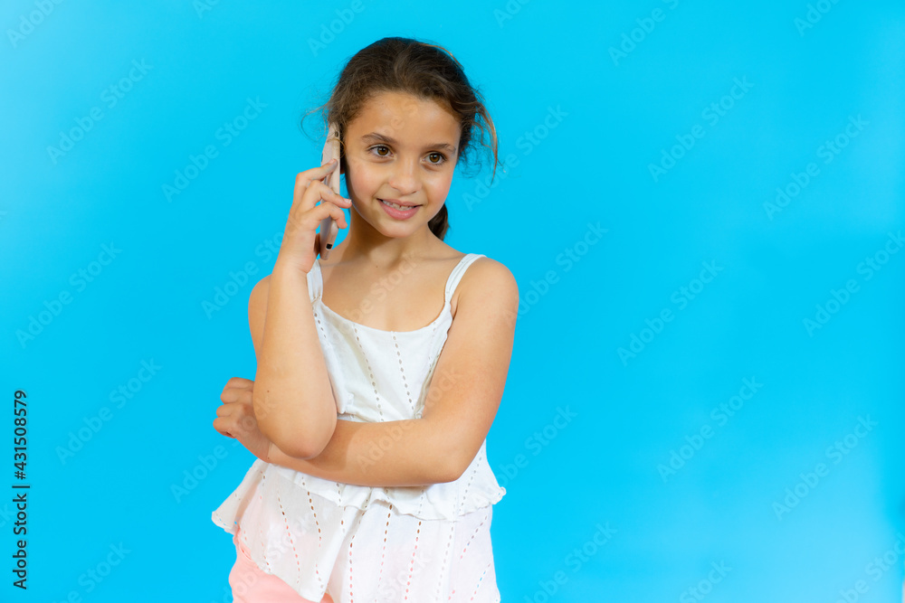 Little girl talking on mobile phone isolated over blue background. Little girl talking on mobile phone isolated over blue background.