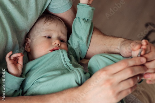 A young father cuts his young son's toenails.Time together.Family concept.Father's Day concept.Paternal care.Newborn care.Paternal care.Newborn care.Close up,selective focus.