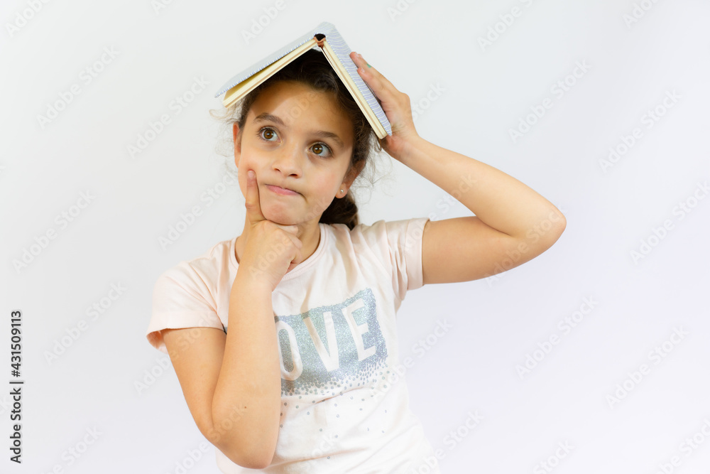 Fototapeta premium Lovely little girl standing and holding a book over white background