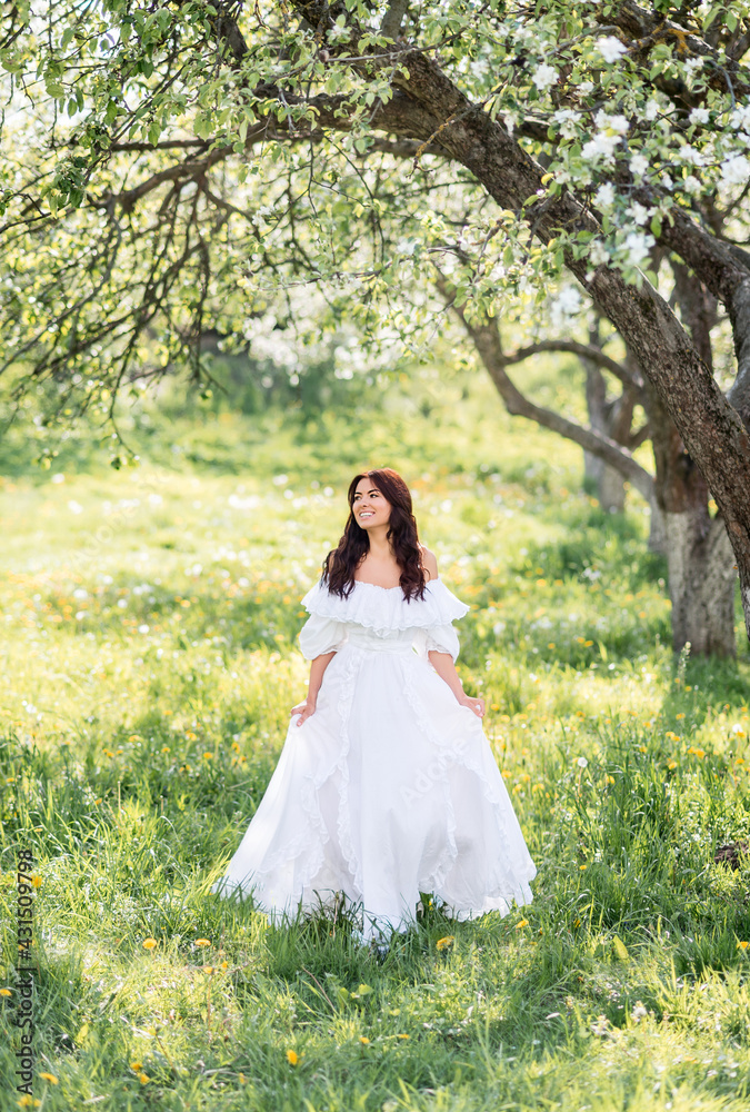 Beautiful woman in a long white dress in a spring garden. A girl runs through a blooming garden.